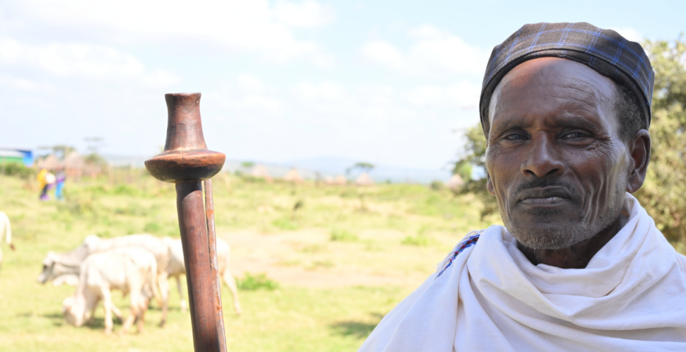 Pastoralist mit Hirtenstock steht vor seinen Tieren.